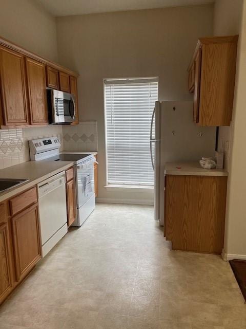 2710 Grants Lake Blvd Unit S4, Sugar Land, TX 77479 - kitchen with white appliances, brown cabinets, tasteful backsplash, light countertops, and baseboards