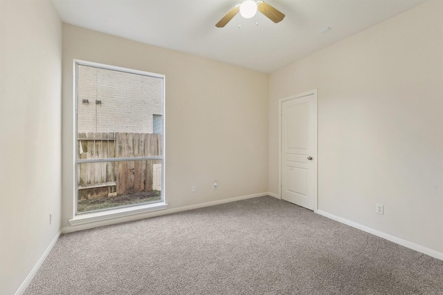carpeted empty room with a ceiling fan and baseboards