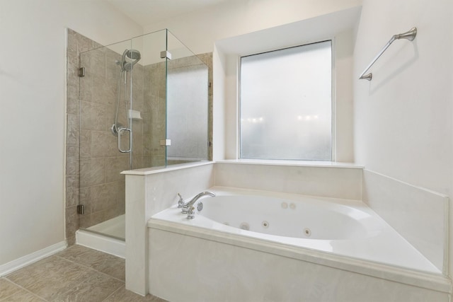 bathroom with a shower stall, a jetted tub, and baseboards
