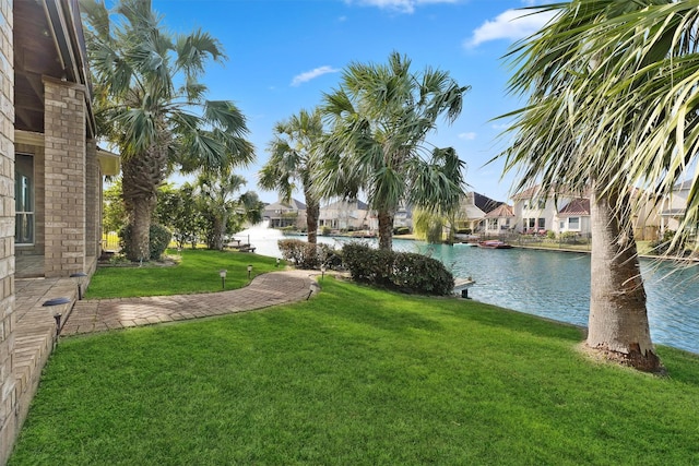 view of green lawn featuring a water view and a residential view