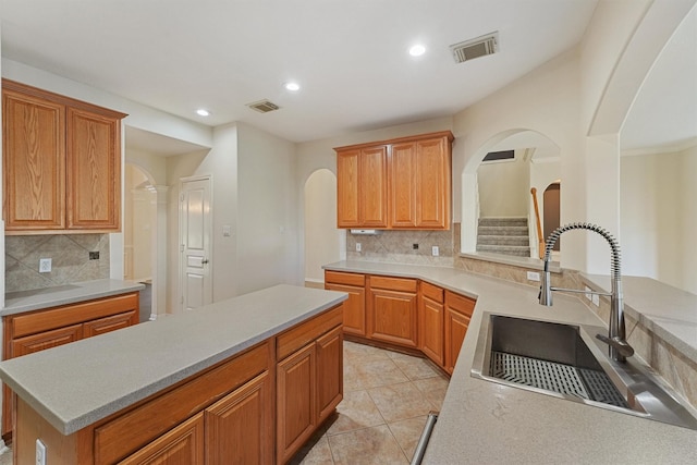 kitchen with arched walkways, a sink, tasteful backsplash, recessed lighting, and light countertops
