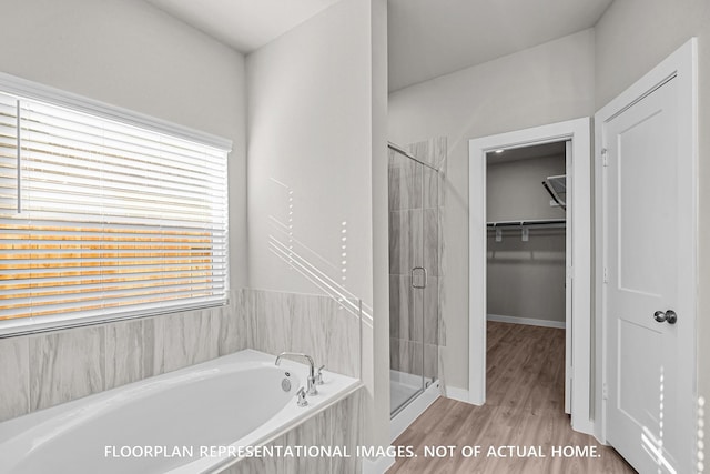 528 Flower Reed Ct, Magnolia, TX 77354 - bathroom with a shower stall, a walk in closet, a garden tub, wood finished floors, and baseboards