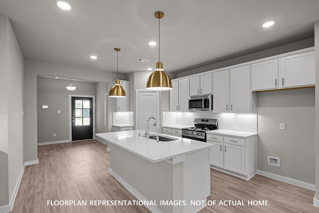 528 Flower Reed Ct, Magnolia, TX 77354 - kitchen featuring appliances with stainless steel finishes, a sink, light wood-style flooring, white cabinets, and decorative backsplash