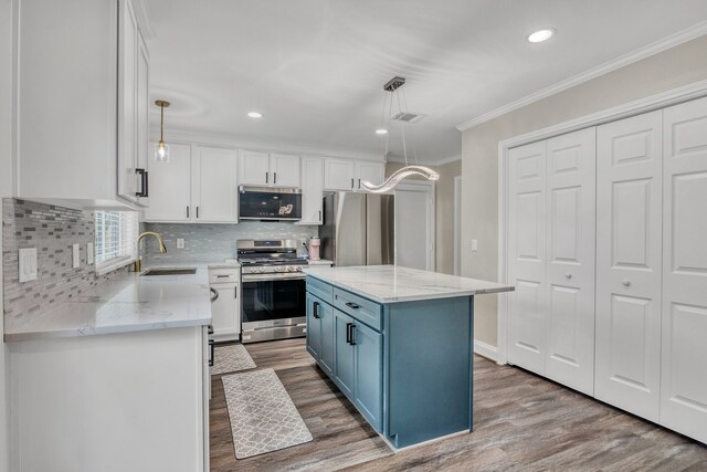 1118 Cheyenne Meadows Dr, Katy, TX 77450 - kitchen with stainless steel appliances, a sink, blue cabinetry, white cabinetry, and crown molding