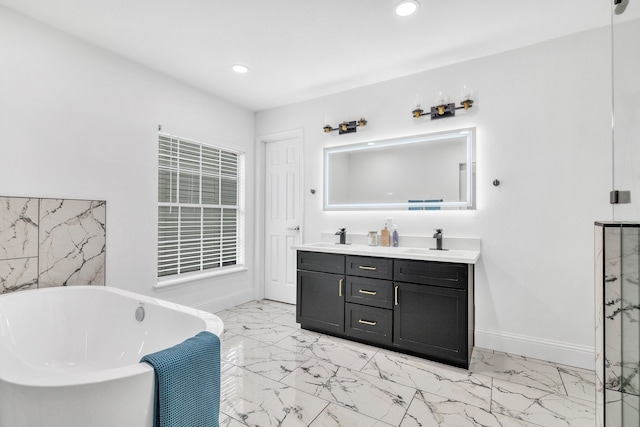 1118 Cheyenne Meadows Dr, Katy, TX 77450 - bathroom featuring marble look tiles, recessed lighting, a soaking tub, double vanity, and baseboards