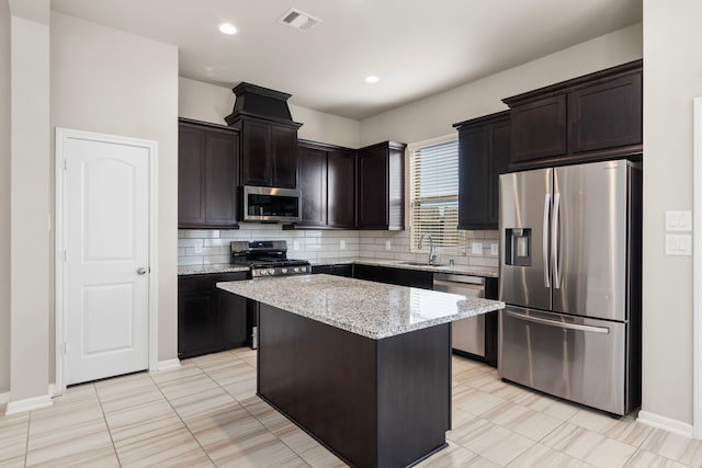 2531 Terrace Point Dr, Missouri City, TX 77459 - kitchen with appliances with stainless steel finishes, a sink, tasteful backsplash, light stone countertops, and a center island