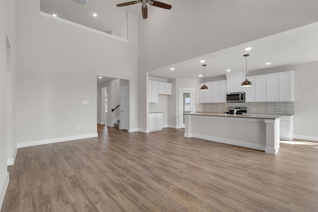21611 Elmheart Dr, New Caney, TX 77357 - unfurnished living room featuring a ceiling fan, light wood finished floors, stairway, recessed lighting, and a towering ceiling