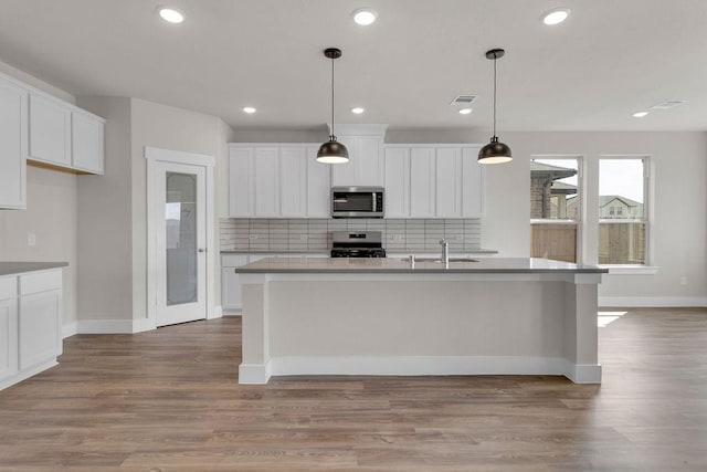 21611 Elmheart Dr, New Caney, TX 77357 - kitchen with stainless steel microwave, range, backsplash, a center island with sink, and recessed lighting