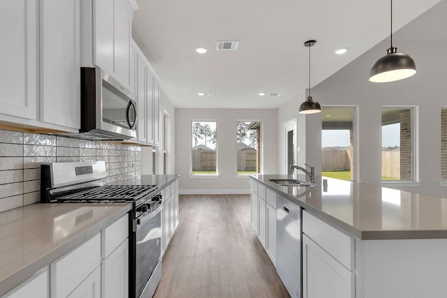 21611 Elmheart Dr, New Caney, TX 77357 - kitchen with stainless steel appliances, backsplash, light wood finished floors, white cabinets, and recessed lighting