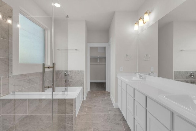 21611 Elmheart Dr, New Caney, TX 77357 - bathroom with double vanity, a garden tub, a spacious closet, a shower with shower door, and marble finish flooring