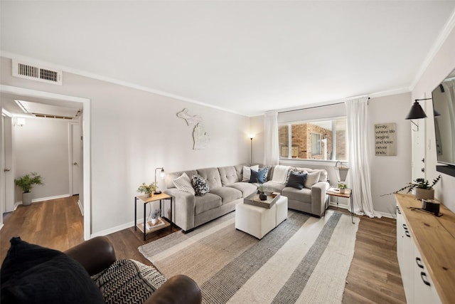 living area with wood finished floors, ornamental molding, and baseboards