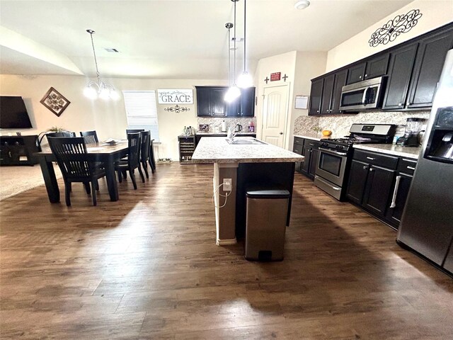 16410 Rodeo River Rd, Houston, TX 77049 - kitchen featuring appliances with stainless steel finishes, decorative backsplash, a sink, a center island with sink, and decorative light fixtures