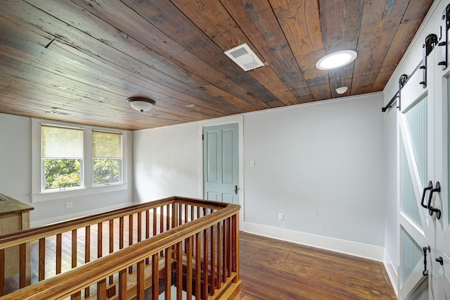 1316 Harvard St, Houston, TX 77008 - hallway with wood ceiling, dark wood-type flooring, baseboards, a barn door, and an upstairs landing