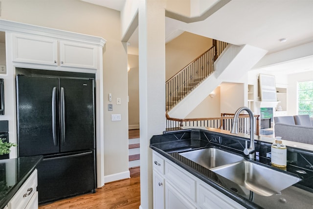 701 Asbury St, Houston, TX 77007 - kitchen with freestanding refrigerator, a sink, white cabinets, light wood-style flooring, and dark stone countertops