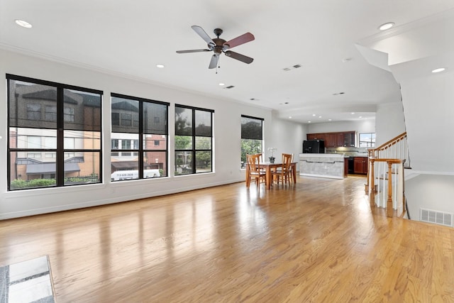 living room with a ceiling fan, recessed lighting, light wood finished floors, stairs, and ornamental molding