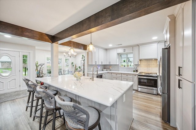 1926 Mapleton Dr, Houston, TX 77043 - kitchen with stainless steel appliances, a kitchen bar, light stone counters, decorative backsplash, and light wood-style floors
