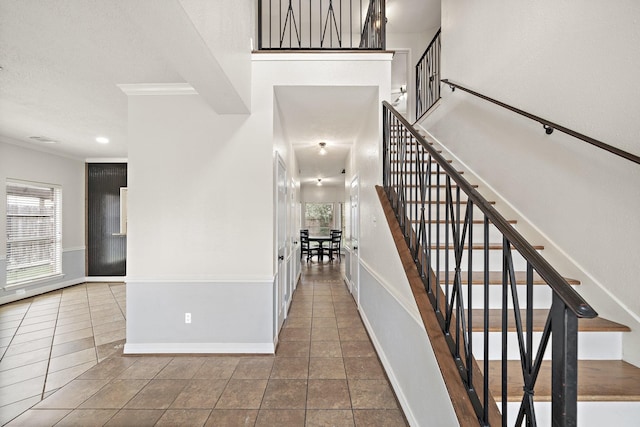 tiled entryway featuring stairs, ornamental molding, and baseboards