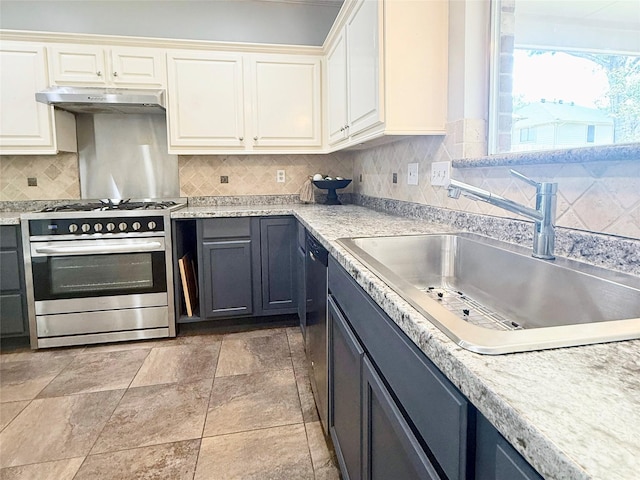 kitchen with stainless steel appliances, a sink, under cabinet range hood, light countertops, and backsplash