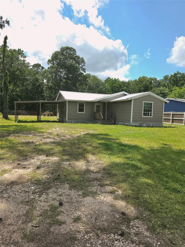 90 Oak Crest Dr, Shepherd, TX 77371 - back of house featuring an attached carport, a yard, metal roof, and view of scattered trees