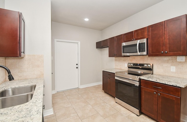 4915 Market St, Houston, TX 77020 - kitchen featuring stainless steel appliances, a sink, decorative backsplash, baseboards, and light tile patterned floors