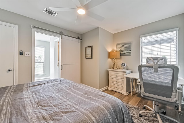 8111 Broadway St Unit 7, Galveston, TX 77554 - bedroom featuring wood finished floors, a barn door, a ceiling fan, and baseboards