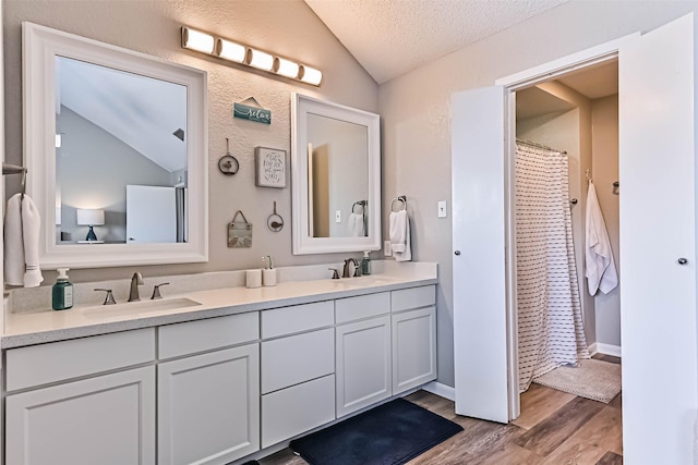 8111 Broadway St Unit 7, Galveston, TX 77554 - bathroom featuring vaulted ceiling, wood finished floors, double vanity, a textured ceiling, and a shower with curtain