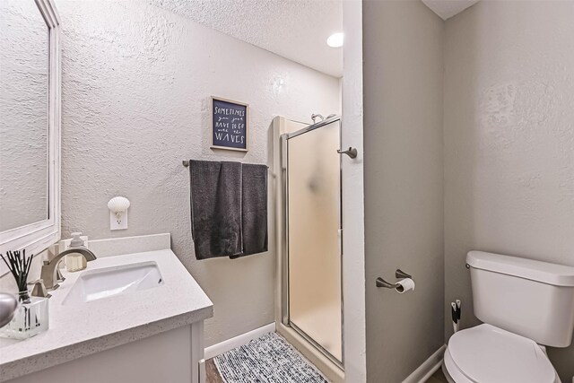 8111 Broadway St Unit 7, Galveston, TX 77554 - bathroom featuring a stall shower, toilet, baseboards, vanity, and a textured ceiling