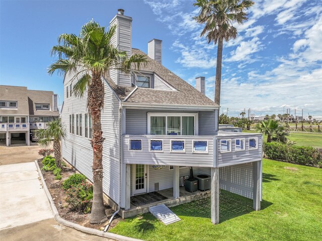 8111 Broadway St Unit 7, Galveston, TX 77554 - back of house with a chimney, a yard, a shingled roof, cooling unit, and a balcony