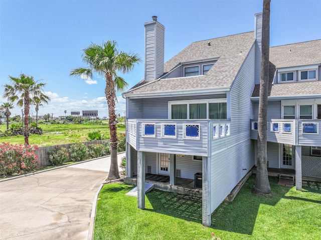 8111 Broadway St Unit 7, Galveston, TX 77554 - rear view of house with a chimney, roof with shingles, and a yard
