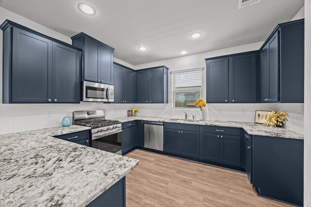 10902 Webber Ln, Texas City, TX 77591 - kitchen featuring stainless steel appliances, a sink, tasteful backsplash, light stone counters, and light wood finished floors