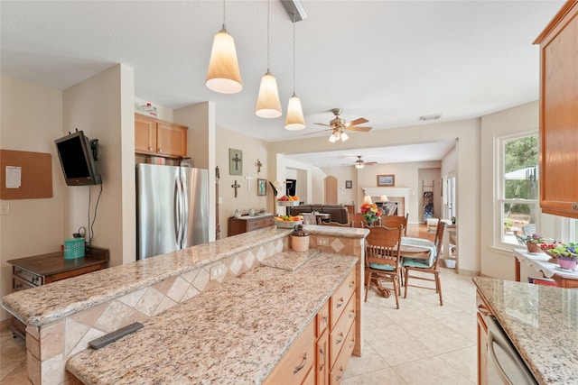 6803 E Treaschwig Rd, Spring, TX 77373 - kitchen featuring freestanding refrigerator, ceiling fan, light tile patterned floors, decorative light fixtures, and light stone counters
