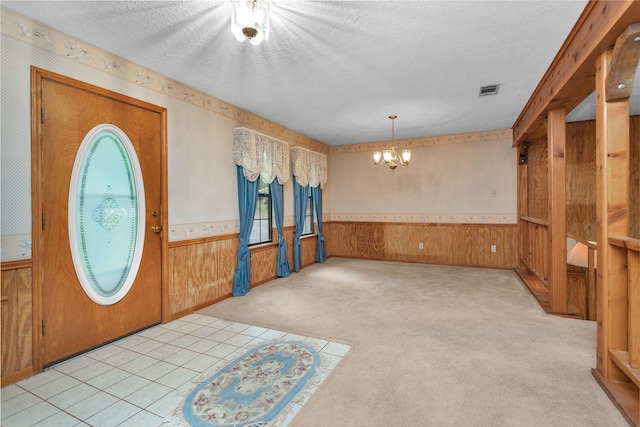 24614 Spruce, Huntsville, TX 77320 - foyer entrance featuring wainscoting, a chandelier, wooden walls, a textured ceiling, and carpet floors
