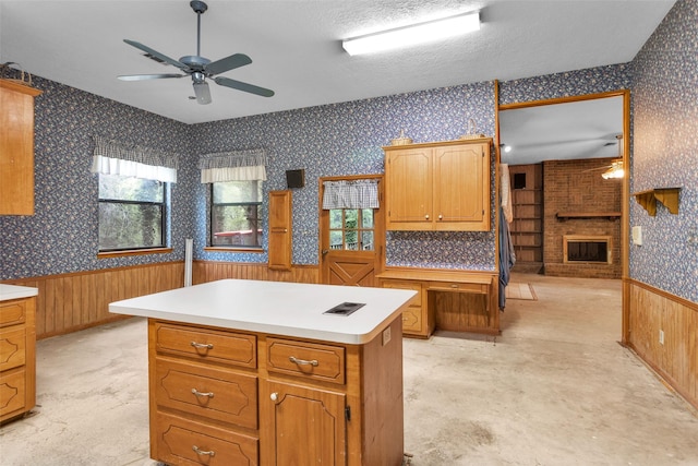 24614 Spruce, Huntsville, TX 77320 - kitchen with wallpapered walls, a ceiling fan, a fireplace, wainscoting, and light countertops