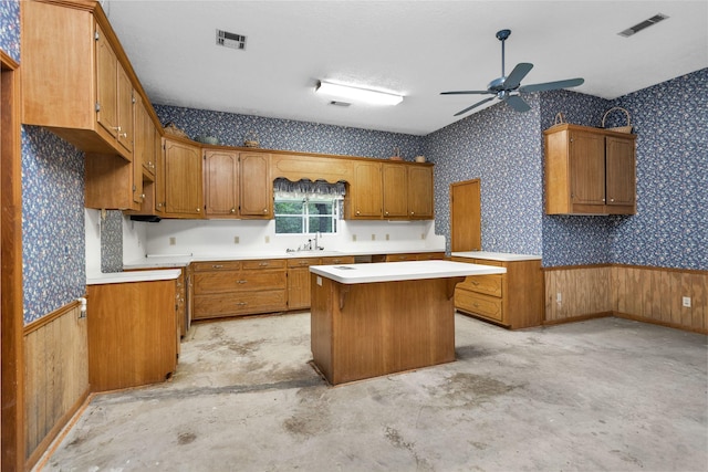24614 Spruce, Huntsville, TX 77320 - kitchen featuring a center island, brown cabinetry, ceiling fan, wallpapered walls, and a sink