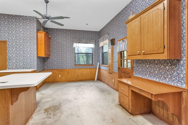 24614 Spruce, Huntsville, TX 77320 - kitchen with wallpapered walls, unfinished concrete flooring, ceiling fan, brown cabinetry, and an office area