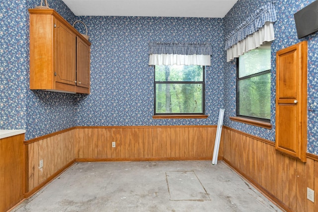 24614 Spruce, Huntsville, TX 77320 - unfurnished room featuring plenty of natural light, wooden walls, wainscoting, concrete floors, and wallpapered walls