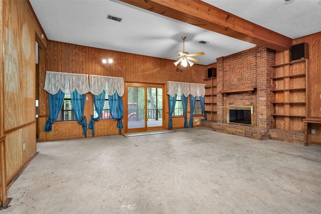 24614 Spruce, Huntsville, TX 77320 - unfurnished living room with wood walls, unfinished concrete floors, a ceiling fan, and a fireplace
