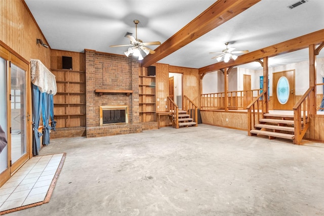 24614 Spruce, Huntsville, TX 77320 - unfurnished living room with stairway, a fireplace, a ceiling fan, wooden walls, and concrete flooring