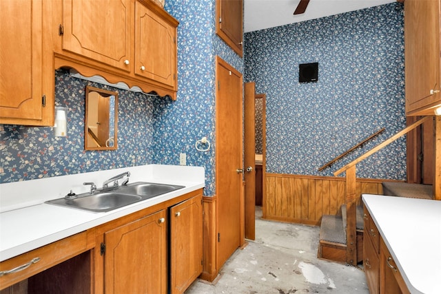 24614 Spruce, Huntsville, TX 77320 - kitchen featuring a sink, wallpapered walls, brown cabinets, light countertops, and a wainscoted wall
