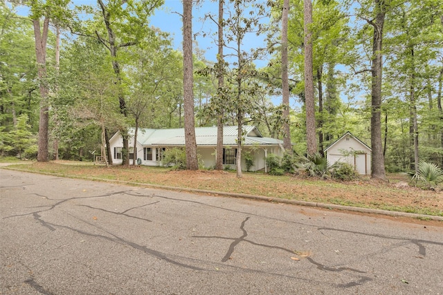 24614 Spruce, Huntsville, TX 77320 - view of front of house with a garage, an outdoor structure, metal roof, and view of scattered trees