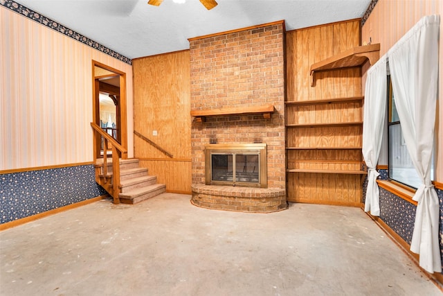 24614 Spruce, Huntsville, TX 77320 - unfurnished living room with wallpapered walls, unfinished concrete flooring, a ceiling fan, a brick fireplace, and stairs