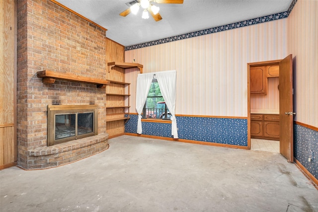 24614 Spruce, Huntsville, TX 77320 - unfurnished living room featuring wallpapered walls, unfinished concrete flooring, a ceiling fan, a fireplace, and a textured ceiling