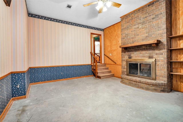 24614 Spruce, Huntsville, TX 77320 - unfurnished living room featuring concrete flooring, wallpapered walls, ceiling fan, stairway, and a fireplace