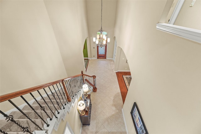 11310 Stonecreek Bend Ln, Cypress, TX 77433 - stairway featuring arched walkways, a chandelier, a high ceiling, and baseboards