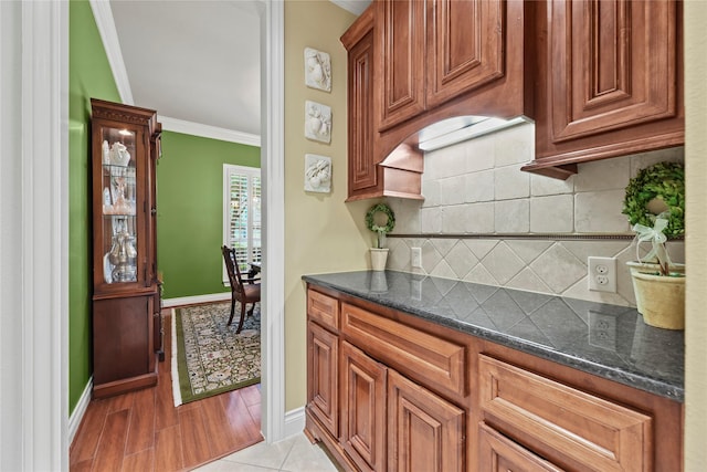 11310 Stonecreek Bend Ln, Cypress, TX 77433 - kitchen with ornamental molding, baseboards, backsplash, dark stone countertops, and brown cabinets