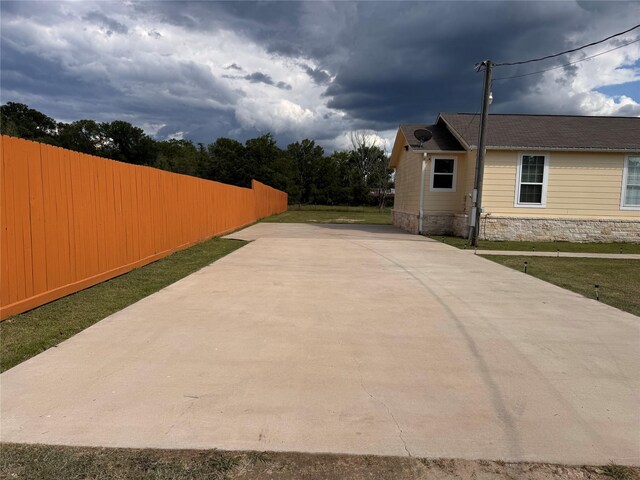 3876 Hummingbird, Bedias, TX 77831 - view of side of property featuring concrete driveway, fence, and stone siding