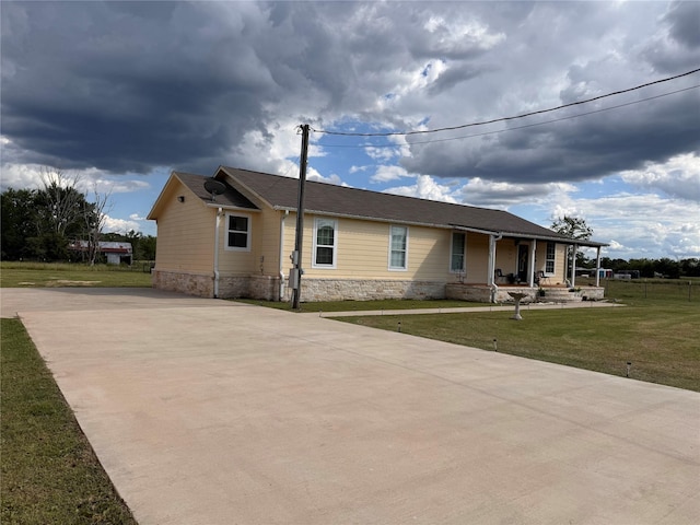 3876 Hummingbird, Bedias, TX 77831 - view of front of home featuring covered porch, driveway, a front yard, and stone siding