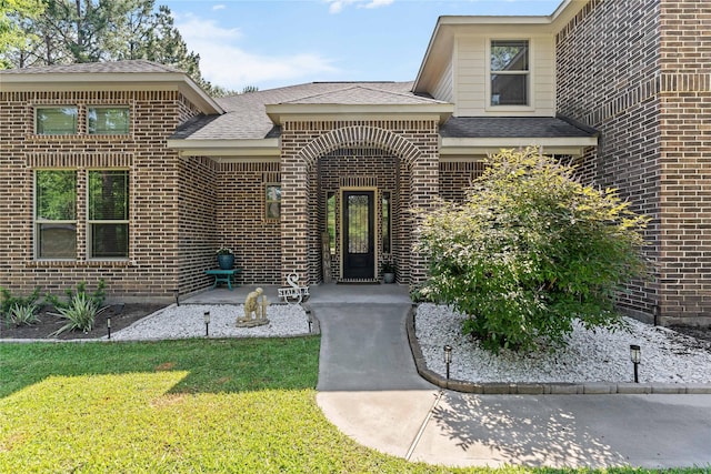 10911 Maddys Ct, Montgomery, TX 77316 - view of exterior entry featuring brick siding, roof with shingles, and a yard