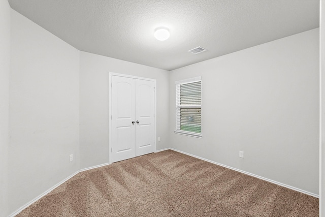 carpeted empty room featuring baseboards and a textured ceiling