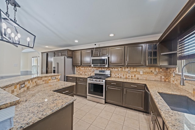 20151 Pioneer Ridge Dr, Cypress, TX 77433 - kitchen featuring stainless steel appliances, arched walkways, dark brown cabinets, light tile patterned floors, and tasteful backsplash